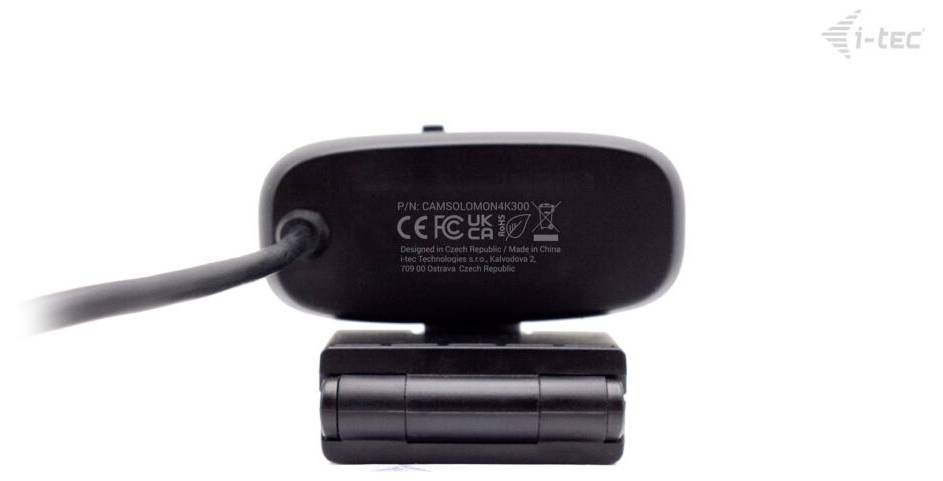 Rückansicht einer schwarzen Webcam mit Zertifizierungslogos und Text „P/N: CAMOBLDOU04K36020". Das Gerät ist auf einem Ständer montiert.