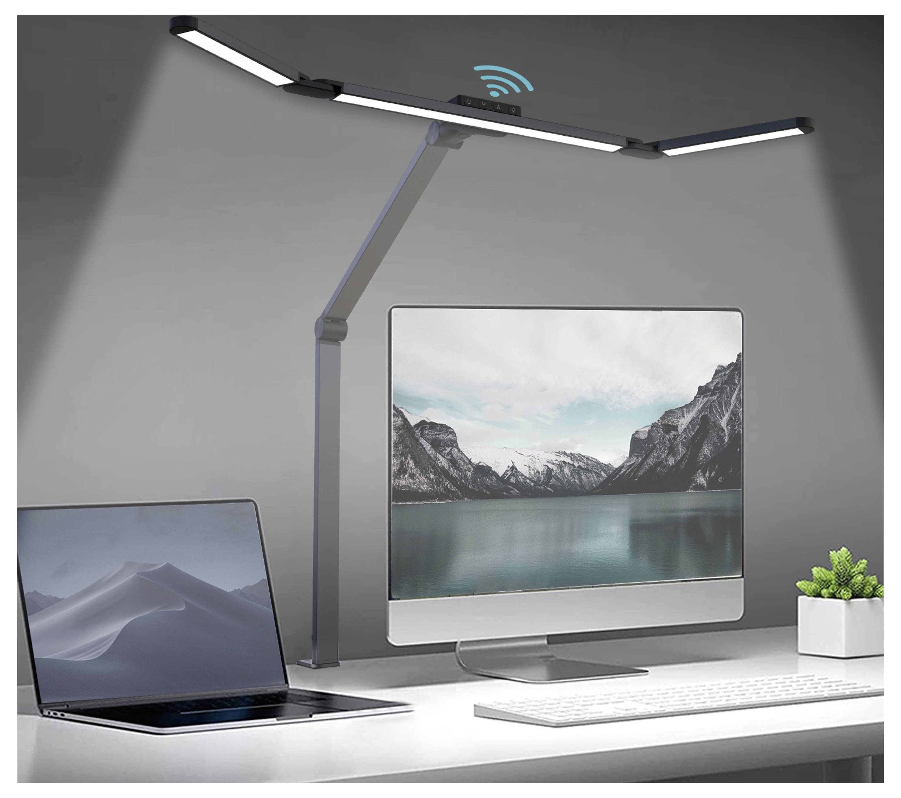 Modernes Schreibtisch-Setup mit Monitor, Laptop, Tastatur und Pflanze unter einer verstellbaren LED-Lampe mit Wireless-Charging-Symbol