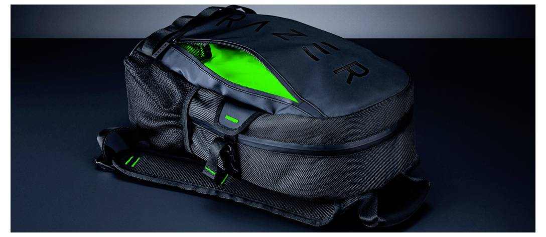 Ein schwarzer Rucksack mit "RAZER" auf der Oberseite, teilweise geöffnet, um ein leuchtendes grünes Inneres zu zeigen. Das Design umfasst Netztaschen und grüne Akzente.