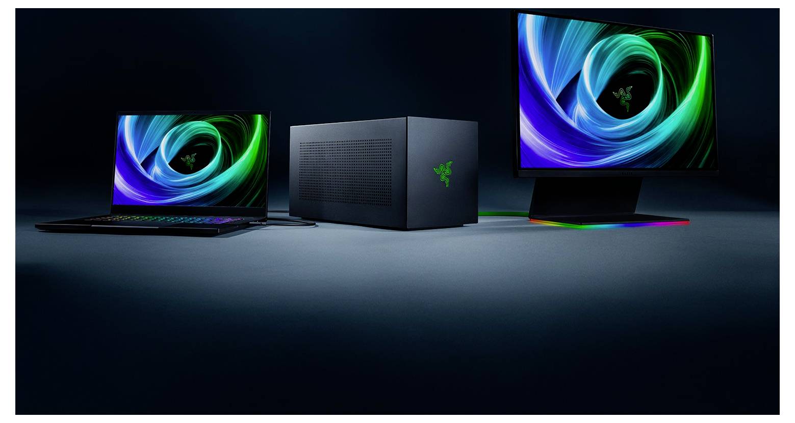 Ein Laptop, ein Desktop-Tower und ein Monitor mit leuchtenden Razer-Logos werden zusammen vor einem dunklen Hintergrund angezeigt.