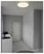 Ein minimalistisches Waschzimmer mit grauen Wänden, weißen Schränken und einer runden Deckenleuchte. Ein Waschbecken und eine Arbeitsplatte sind auf der linken Seite.