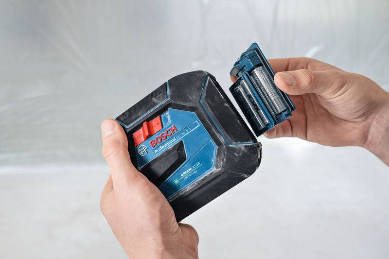 Eine Person hält ein Bosch-Lithium-Ionen-Akku-Pack und seine abgenommene Abdeckung, die die Batteriezellen zeigt, vor einem neutralen Hintergrund.