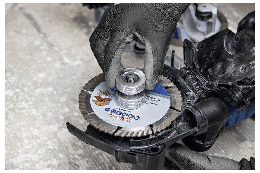 Eine behandschuhte Hand installiert ein Metallschneidblatt auf einer Elektrosäge, die auf einer Werkbank liegt.