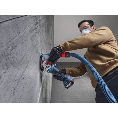 Eine Person, die Schutzausrüstung trägt, verwendet ein Elektrowerkzeug zum Schneiden einer Betonwand und demonstriert konzentrierte Anstrengung und Präzision bei einer Bauaufgabe.
