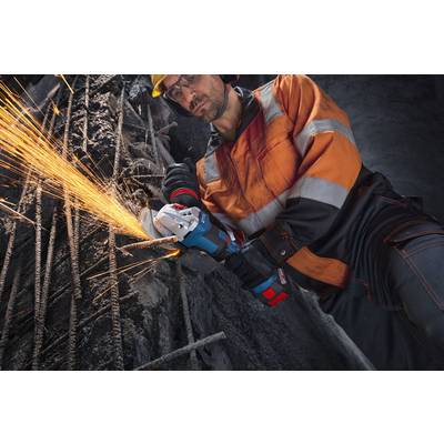 Ein Arbeiter in Schutzausrüstung schleifen Metallstangen mit einem Elektrowerkzeug und erzeugt dabei Funken auf einer Baustelle.