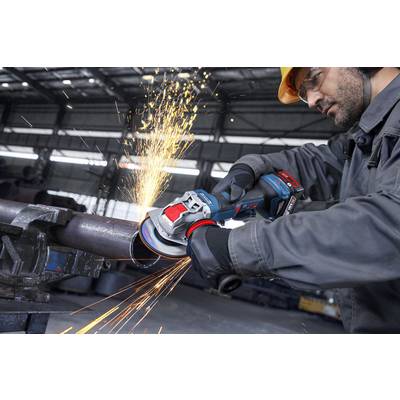 Arbeiter, der eine Winkelschleifer auf einem Metallrohr einsetzt, Funken fliegen, in einer Industriewerkstatt, trägt Schutzausrüstung einschließlich Helm und Handschuhe.