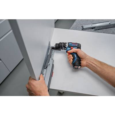 Eine Person benutzt einen Elektroschrauber, um eine Schubladenschiene an einem Schrank anzubringen. Es scheint sich um eine Heimwerker- oder Möbelmontageaufgabe zu handeln.
