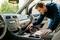 Eine Person, die das Innere eines Autos absaugt und sich auf den Bereich zwischen den Vordersitzen konzentriert, um Sauberkeit und Hygiene zu gewährleisten.