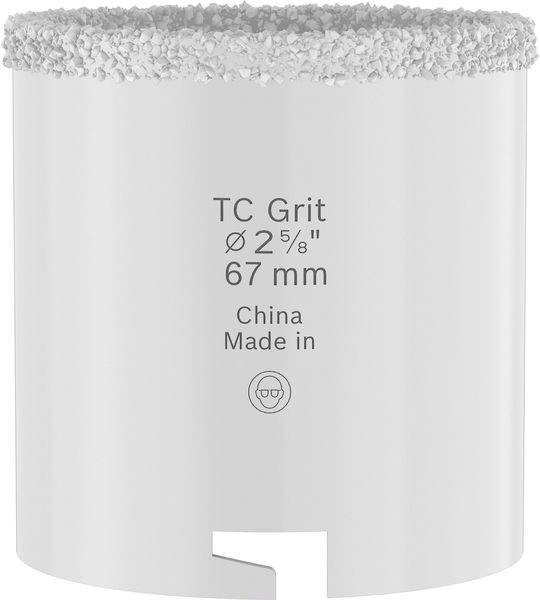 Eine Nahaufnahme eines weißen zylindrischen Werkzeugs mit der Beschriftung „TC Grit Ø 2⅝" 67 mm, China, Made in" mit einer strukturierten oberen Kante, wahrscheinlich ein Bohrer oder eine Lochsägen-Aufsatz.