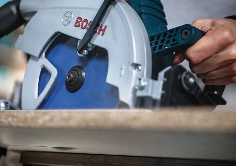 Eine Person bedient eine blau-silberne Elektrosäge zum Zuschneiden von Holz und demonstriert dabei Präzision und Konzentration bei einer Bau- oder DIY-Aufgabe.