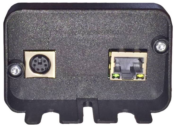 Ein schwarzes elektronisches Anschlussfeld mit einem 6-poligen Rundstecker auf der linken Seite und einem Ethernetanschluss auf der rechten Seite, beide umgeben von Schrauben.