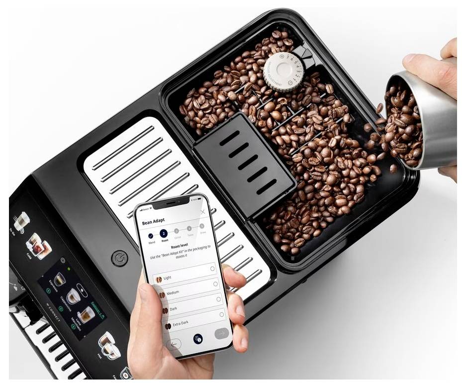 Eine Person gießt Kaffeebohnen in eine Mühle, während sie ein Smartphone hält, auf dem eine Kaffee-App angezeigt wird, die Optionen für verschiedene Kaffeeeinstellungen zeigt.