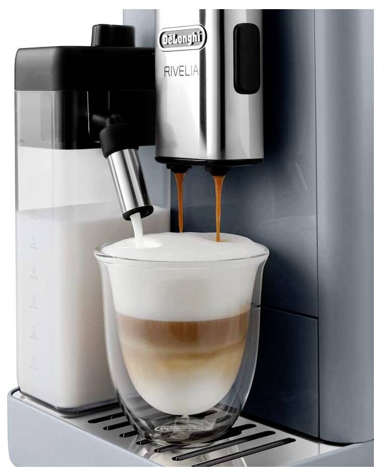 Eine Kaffeemaschine mit Milchaufschäumer und doppelten Espressoströmen füllt ein Glas mit geschichtetem Cappuccino und zeigt cremigen Schaum an der Oberseite.