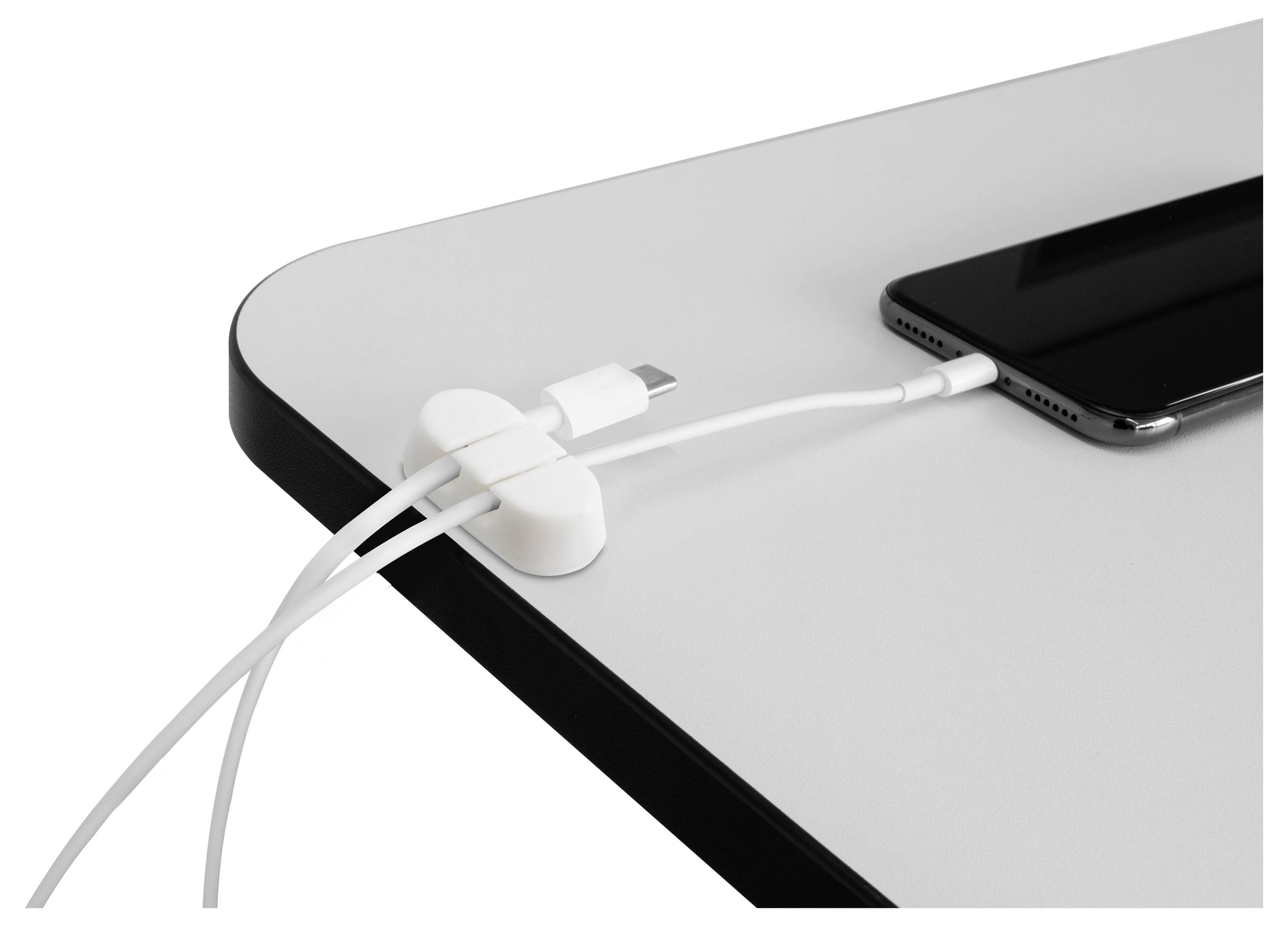 Ein Smartphone lädt auf einem Tisch mit zwei weißen Kabeln, die von einem Magnethalter organisiert werden.