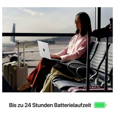 Frau arbeitet am Laptop im Flughafen, neben Koffer und Gepäck; unten steht 'Bis zu 24 Stunden Batterielaufzeit' neben Batteriesymbol.