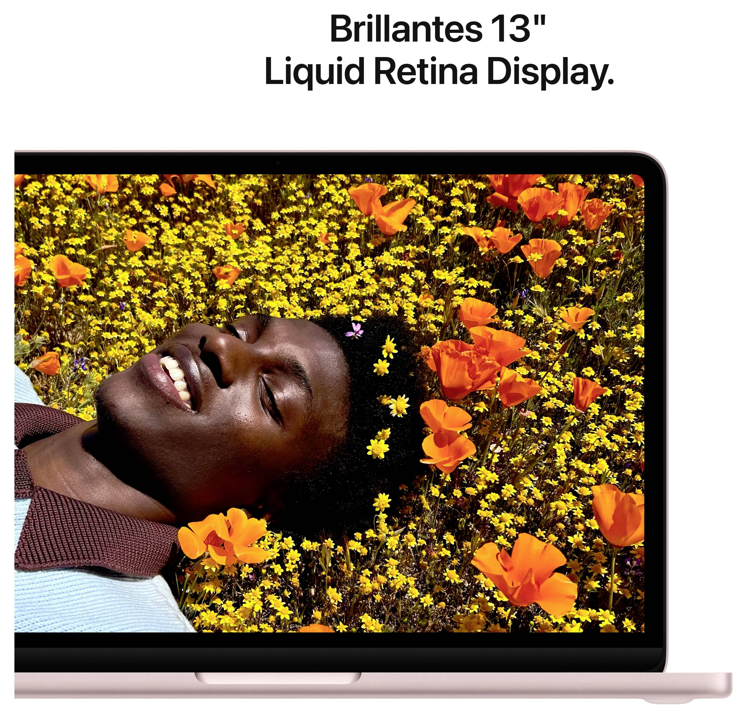 Person mit einem Lächeln liegt auf einem Feld mit gelben und orangefarbenen Blumen, auf einem Laptop-Bildschirm mit der Aufschrift 'Brillantes 13" Liquid Retina Display'.