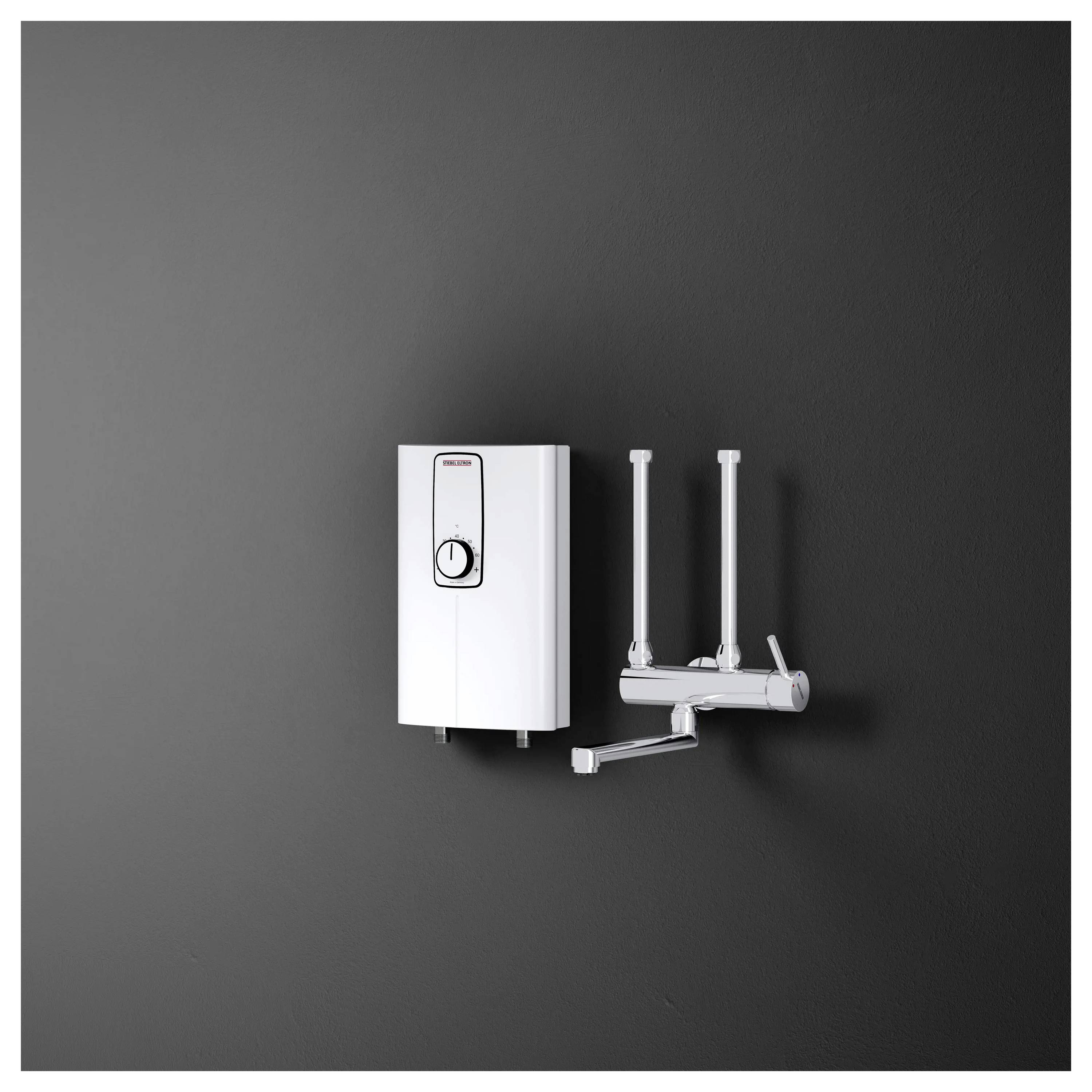 Ein an der Wand montierter weißer tankloser Warmwasserbereiter mit Doppelarmatur auf dunklem Hintergrund, der sein kompaktes Design und die Rohrleitungsanlage zeigt.