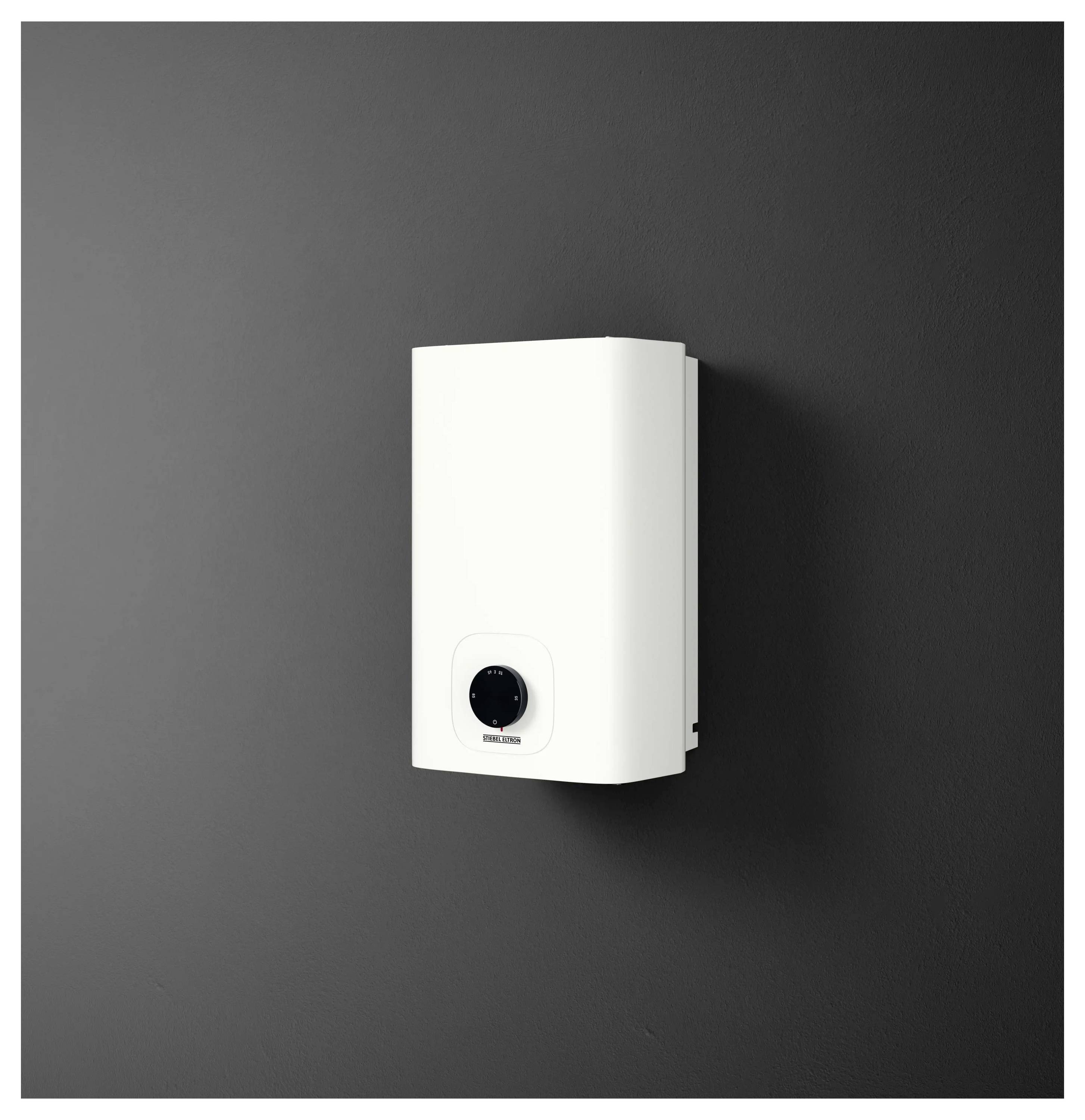Ein weißes, rechteckiges, wandmontiertes elektrisches Warmwasserspeichersystem mit einer Bedienungsdrehknopf vor dunklem Hintergrund.