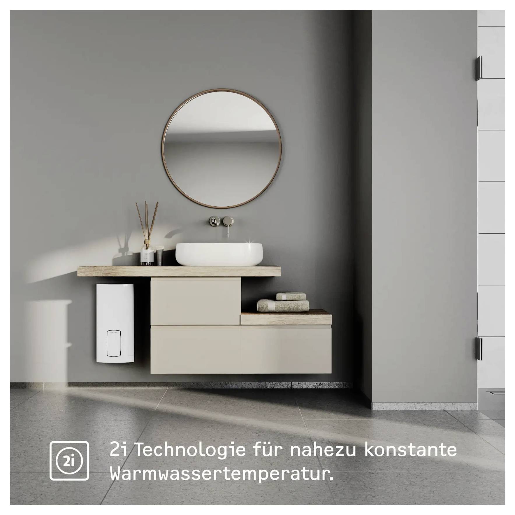 Ein modernes Badezimmer mit einem runden Spiegel, Waschbecken auf einer Holzarbeitsplatte und einem weißen Panel an der Wand. Der Text lautet: „2i Technologie für nahezu konstante Warmwassertemperatur."