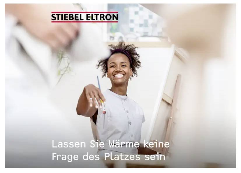 Eine lächelnde Person im weißen Hemd hält einen Pinsel. Der Text lautet: Lassen Sie Wärme keine Frage des Platzes sein mit dem Logo „STIEBEL ELTRON".