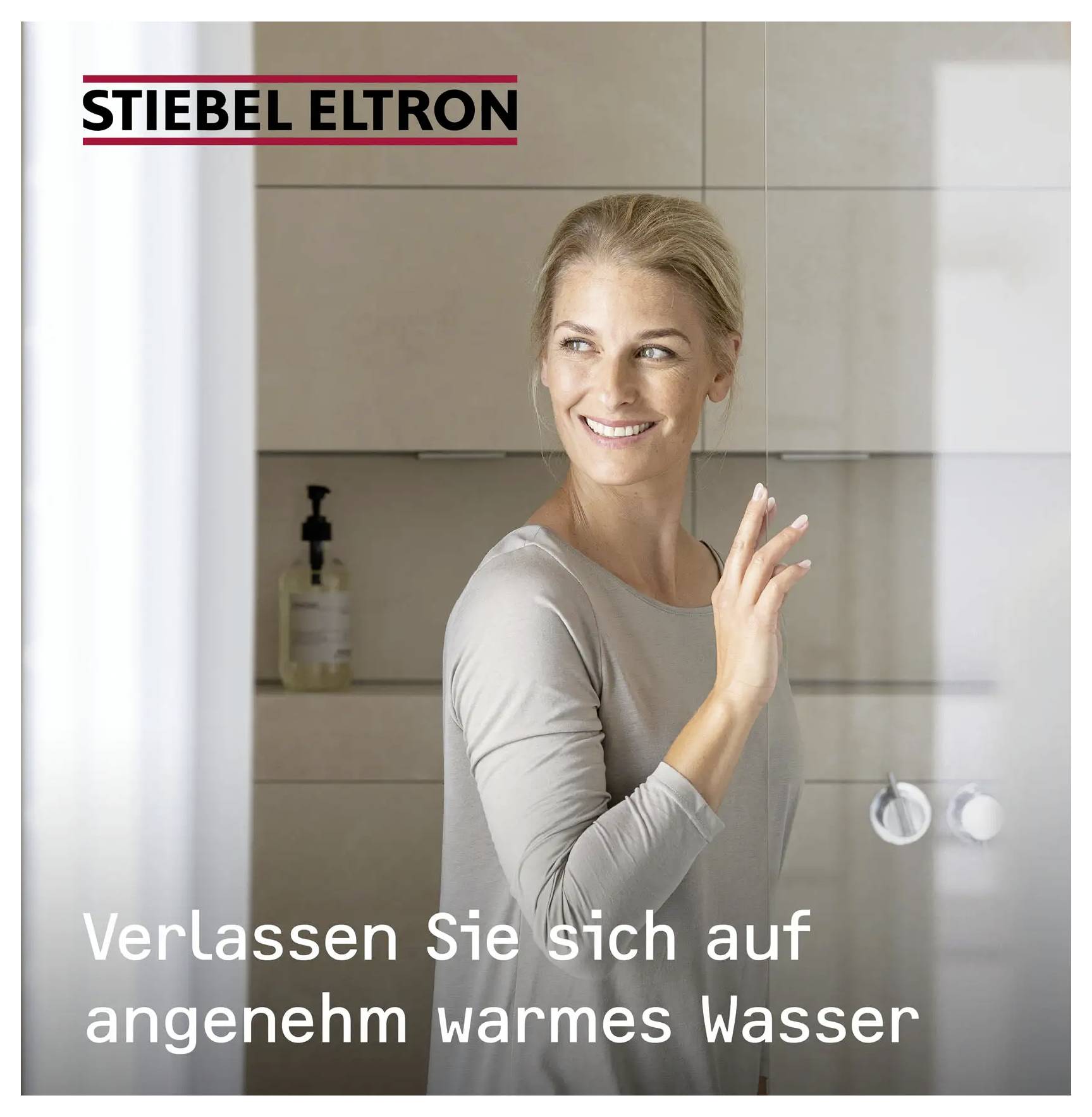 Eine Person im Badezimmer lächelt und berührt eine Duschsteuerung. Der Text besagt „Verlassen Sie sich auf angenehm warmes Wasser" unter der Marke „Stiebel Eltron".