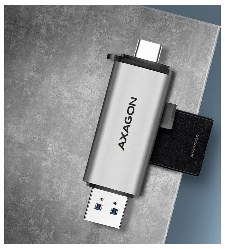 Silberner AXAGON USB-Stick mit dualen Anschlüssen, gezeigt auf einer strukturierten grauen Oberfläche mit angebrachtem schwarzem Adapter