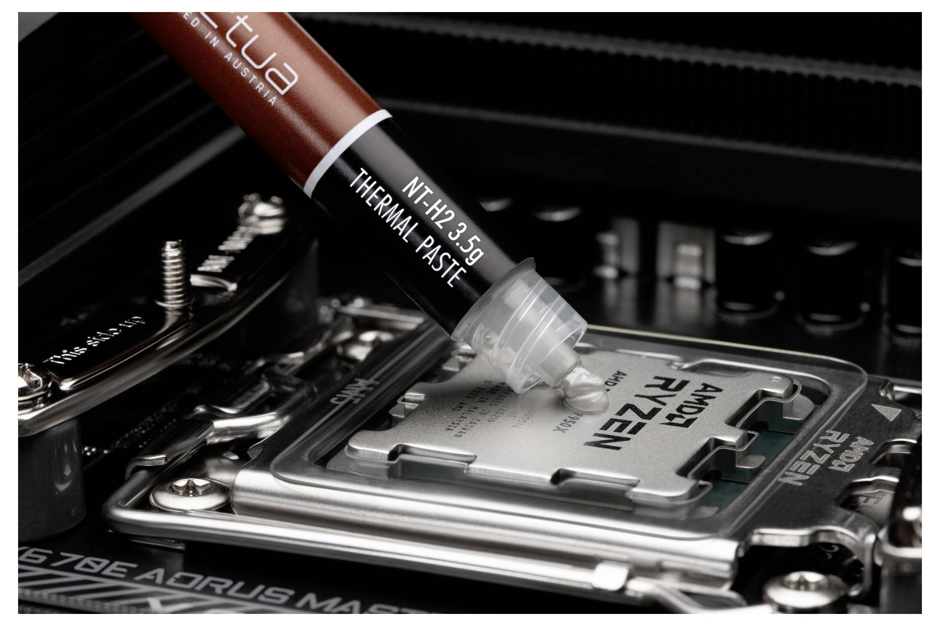 Noctua NT-H2 3,5g Wärmeleitpaste wird auf eine AMD Ryzen CPU auf einem Motherboard aufgetragen.