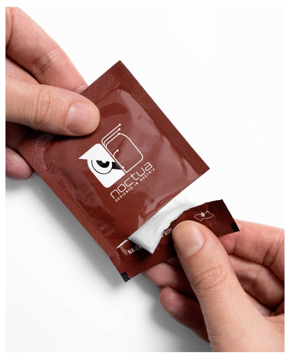 Hände reißen eine braune "Noctua"-Packung auf und enthüllen dabei einen weißen Beutel im Inneren auf weißem Hintergrund.