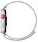 Seitenansicht einer Smartwatch mit einer kreisförmigen Krone, einem Knopf und einem geflochtenen Solo Loop-Armband in einer neutralen Farbe.