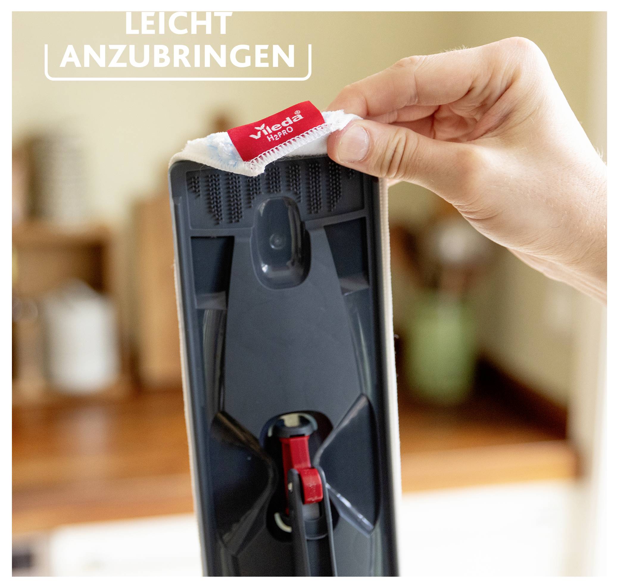 Eine Hand befestigt einen Mop-Ersatz mit der Bezeichnung „Vileda 1-2 Spray" an einem Mopkopf. Der Text „Leicht anzubringen" zeigt an, dass er einfach anzubringen ist.