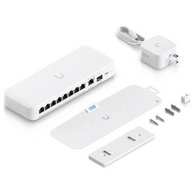 „Ubiquiti-Netzwerk-Switch mit mehreren Ethernet-Anschlüssen, Netzteil, Befestigungswinkel, Schrauben und Zubehör, angeordnet auf weißer Oberfläche."