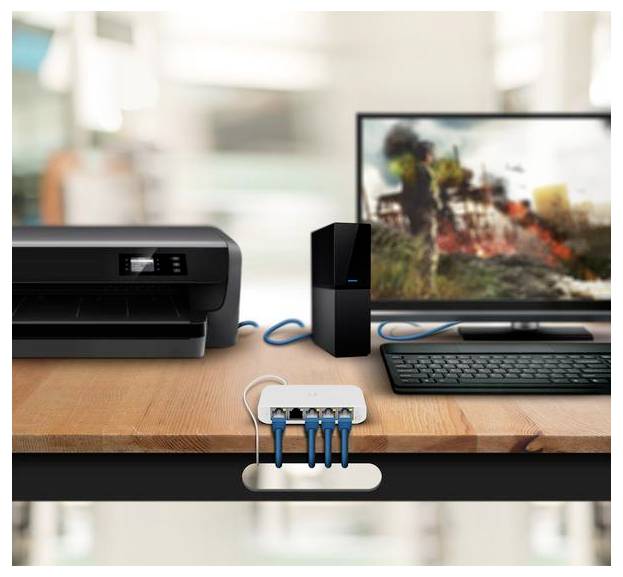 Ein Schreibtisch mit einem Drucker, einem Monitor, auf dem ein verschwommenes Bild angezeigt wird, einer Tastatur und einem kleinen Netzwerkgerät, die durch Kabel verbunden sind.