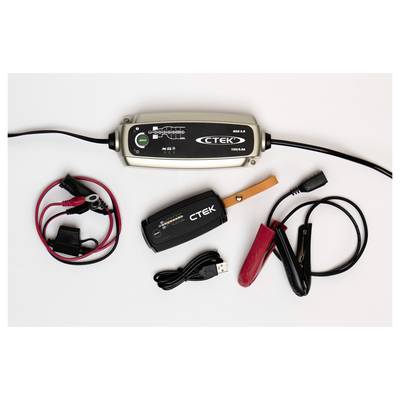 Ein Batterie-Ladegerät-Set mit Hauptgerät, Krokodilklemmen und USB-Kabel auf einer weißen Oberfläche.