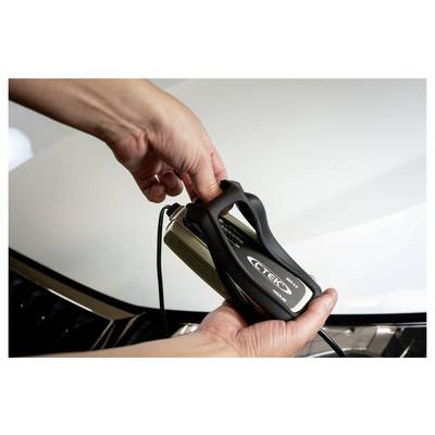 Person, die ein Autoladegerät mit "CTEK"-Logo hält, stellt Einstellungen ein, möglicherweise um eine Fahrzeugbatterie zu laden.