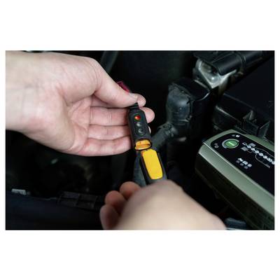 Eine Person, die einen Spannungsprüfer im Motorraum eines Autos verwendet, um elektrische Verbindungen zu überprüfen.