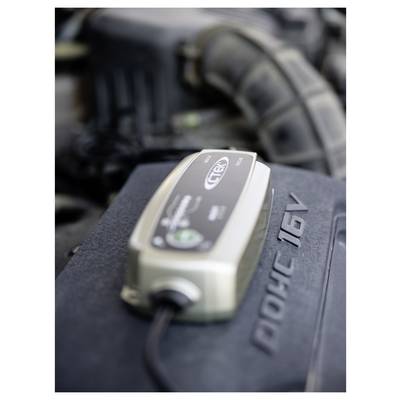 Ein Batterieladegerät, das mit einem Automotor verbunden ist und die Batteriewartung oder den laufenden Ladevorgang anzeigt.