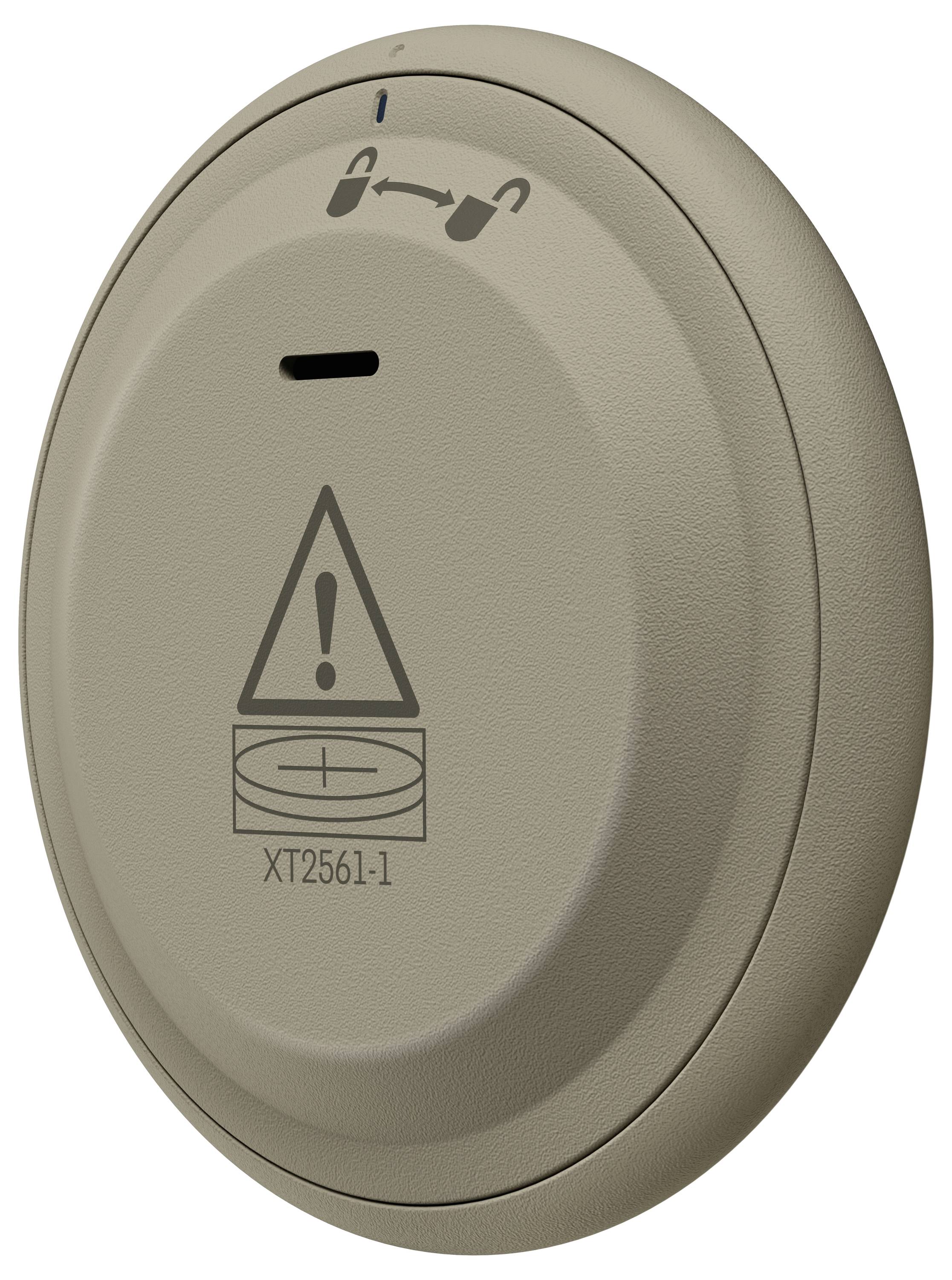Eine runde, beige Batterikappe mit einem Warnsymbol und der Aufschrift "XT2561-1". Ein Symbol oben zeigt eine Wechsel- oder Rotationsanleitung.