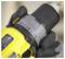 Eine Person in einem pelzgefütterten Wintermantel und Handschuhen stellt Einstellungen an einem gelben Schneefräser mit der Aufschrift „STANLEY" auf einer verschneiten Oberfläche ein.
