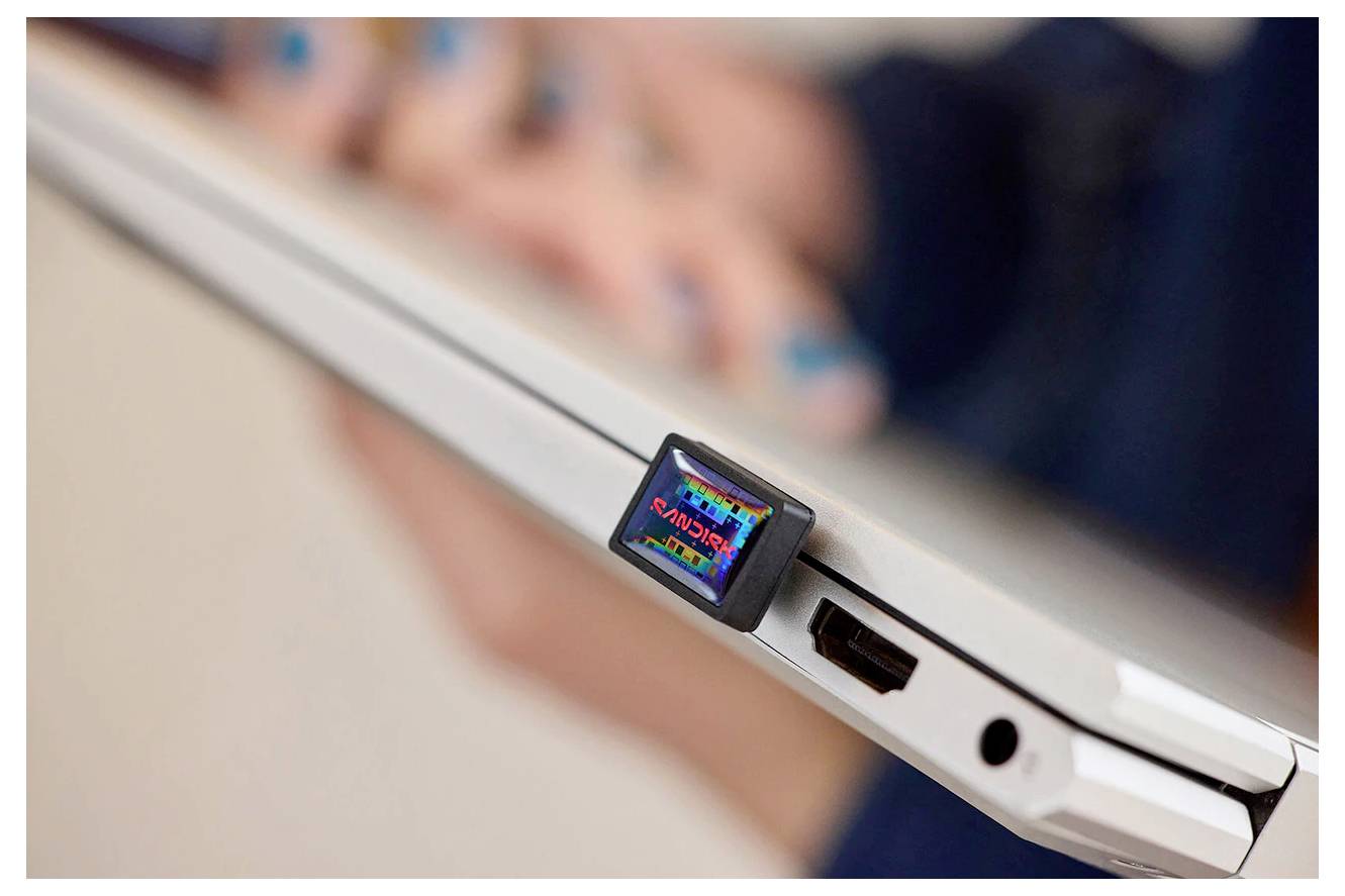 Eine Nahaufnahme eines Laptops mit einem in einen Anschluss eingesteckten USB-Gerät mit der Bezeichnung "Planex", das von einer Person gehalten wird.