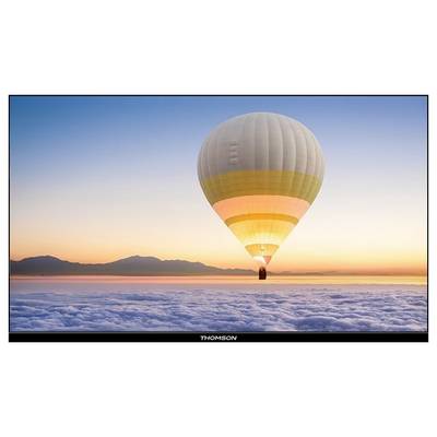 Ein Heißluftballon schwebt über einer wolkenbedeckten Landschaft bei Sonnenaufgang, mit entfernten Bergen am Horizont.