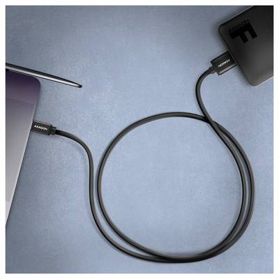 Laptop, der über ein USB-C-Kabel mit einem Smartphone auf einer blauen Oberfläche verbunden ist und eine Daten- oder Ladeverbindung anzeigt.
