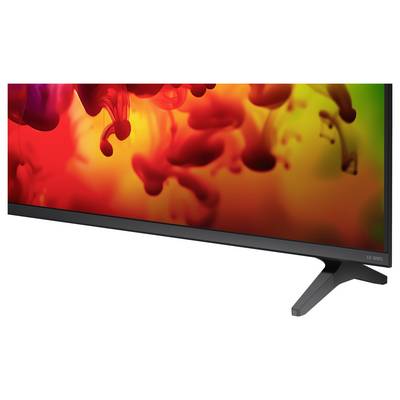 Flachbildfernseher mit lebendiger rot, orange und grüner abstrakter Anzeige auf einem Ständer vor weißem Hintergrund.