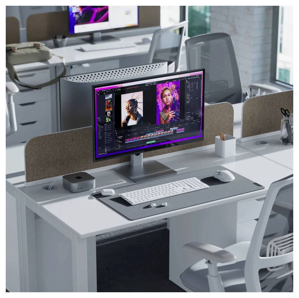 Moderner Büroarbeitsplatz mit einem Monitor, der eine Fotobearbeitungs-Timeline und Porträtbilder anzeigt, Tastatur, Maus und Schreibtischaccessoires in einem offenen Arbeitsbereich.
