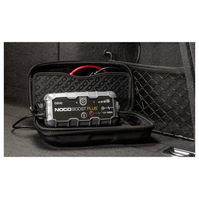 Ein NOCO Boost Plus GB40 Starthilfegerät in einer schwarzen Tasche mit Reißverschluss mit Kabeln und Klemmen, auf einer dunklen Oberfläche aufgeklappt dargestellt.
