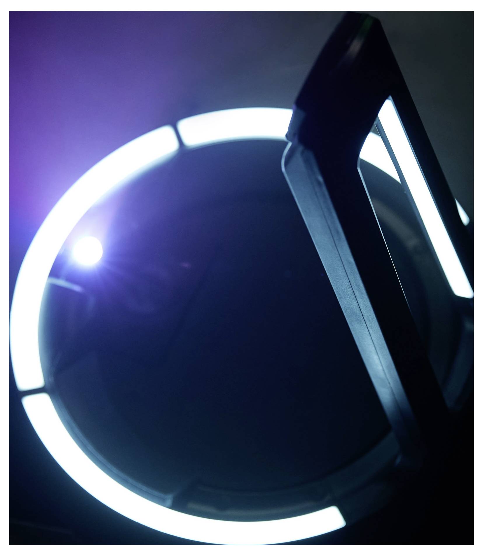 Nahaufnahme eines leuchtenden weißen Ringlichts vor dunklem Hintergrund, teilweise verdeckt durch ein schwarzes Objekt.