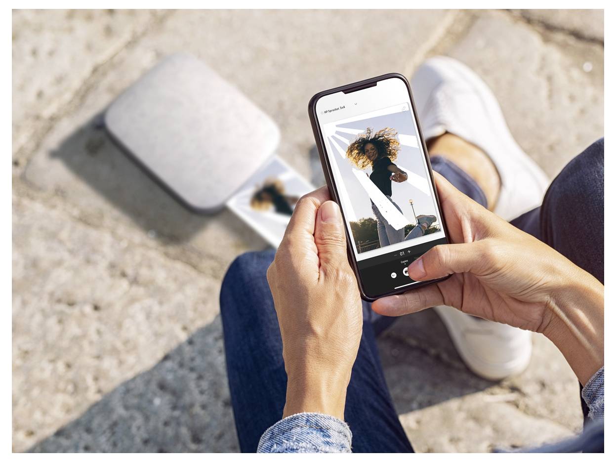 Eine Person, die ein Smartphone hält und ein Foto einer Frau betrachtet, die draußen posiert, während sie auf Stufen in der Sonne sitzt.