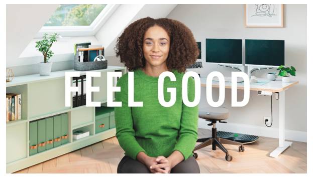 Lächelnde Frau in einem Heimbüro mit den Worten „FEEL GOOD" über dem Bild.