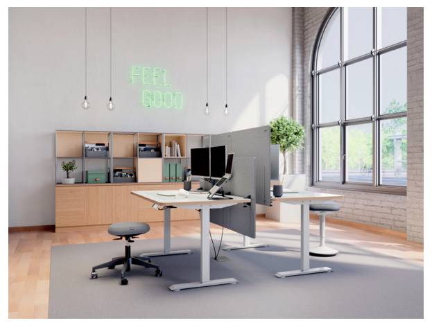 Modernes Open-Office mit höhenverstellbaren Schreibtischen, Computermonitoren, Regalen und einem leuchtenden Neon-Schild mit der Aufschrift „FEEL GOOD" neben großen Bogenfenstern