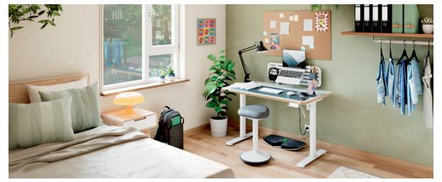 Ein ordentliches Schlafzimmer-Arbeitsplatz mit einem Bett, Schreibtisch, Hocker, Computer, Pinnwand, Pflanze und hängenden Kleidern an der Wand.