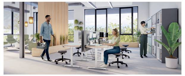 Modernes Großraumbüro mit einem Mann, der eine Aktentasche trägt und an einer Frau vorbeigeht, die an einem Schreibtisch arbeitet, mit Spinden und Pflanzen im Hintergrund.